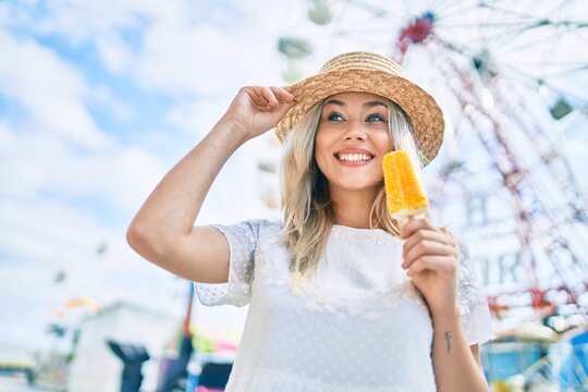 Young caucasian tourist girl smiling happy and eating ice cream at fairground.