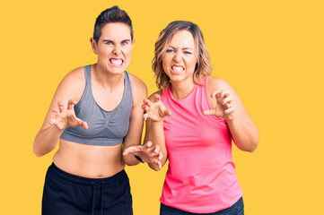 Couple of women wearing sportswear smiling funny doing claw gesture as cat, aggressive and sexy expression