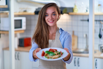 Portrait of a beautiful happy cute joyful smiling cooking chef woman with a plate of fresh salad
