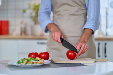 Cooking woman cutting ripe fresh eco friendly juicy tomatoes on a wooden board using a knife