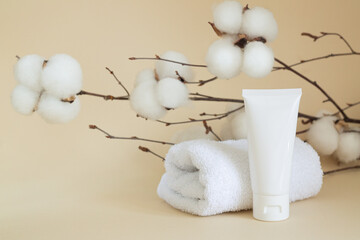 Blank white cosmetic tube next to towel
