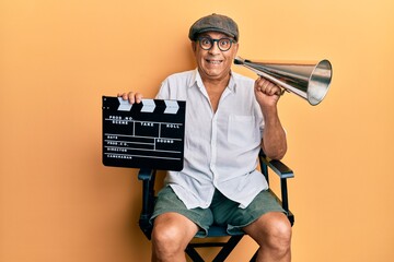 Handsome mature director man holding video film clapboard and louder smiling and laughing hard out...