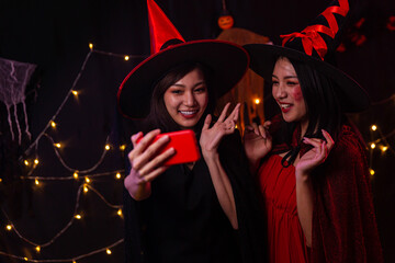 Obraz premium Women wear witch costumes for Halloween. Young women are using mobile phones. Halloween festival