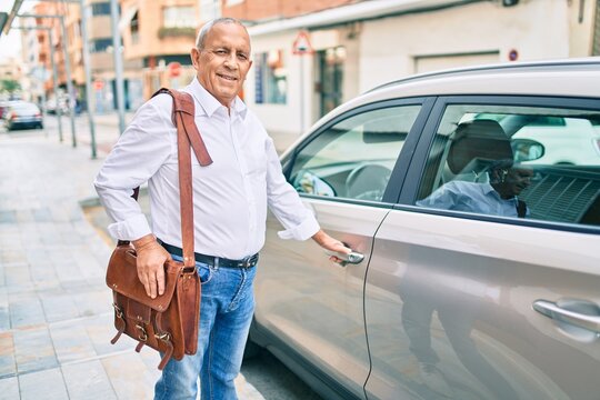 Senior man smiling happy opening car at the city.