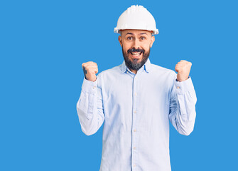 Young handsome man wearing architect hardhat celebrating surprised and amazed for success with arms raised and open eyes. winner concept.