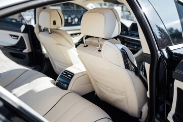 The back seat of a premium car. Beige leather and control system