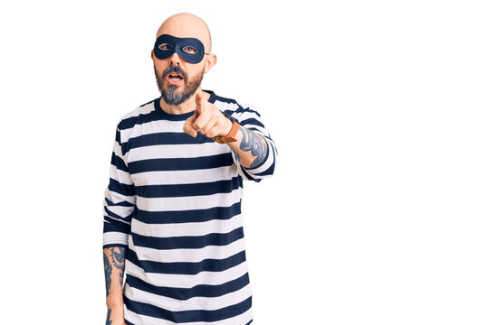 Young handsome man wearing burglar mask pointing displeased and frustrated to the camera, angry and furious with you