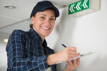 happy female technician writing on clipboard