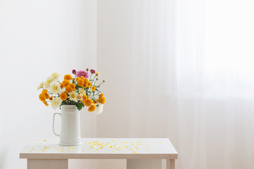 chrysanthemum flowers in white jug on background white wall