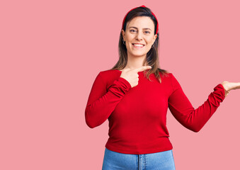 Young beautiful woman wearing casual clothes amazed and smiling to the camera while presenting with hand and pointing with finger.