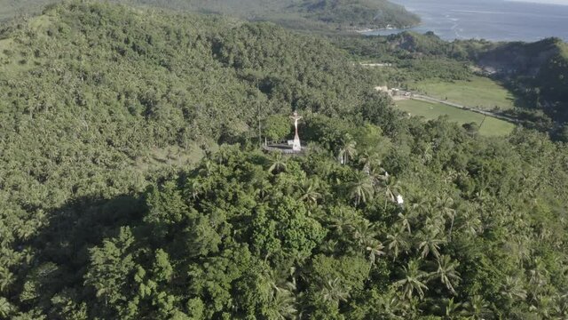 Sacred Religious Cross Of Christ The Redeemer On Top Of The Mountain With Blue Ocean At The Background In  Southern Leyte, Philippines During Sunset. - Aerial Drone Pullback Shot