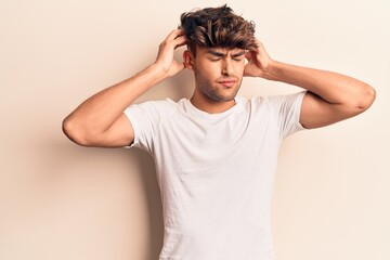 Young hispanic man wearing casual clothes with hand on head, headache because stress. suffering migraine.