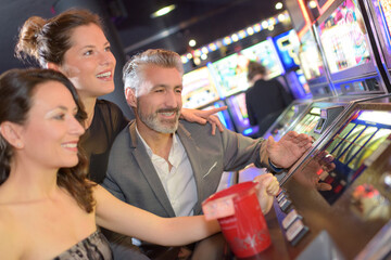 three adults having fun on casino slot machines