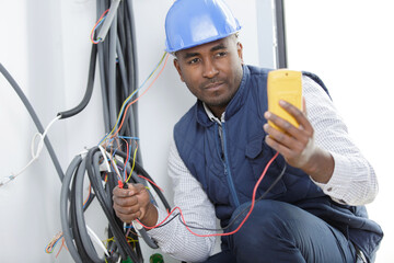 male electrician checking wiring with a multimeter