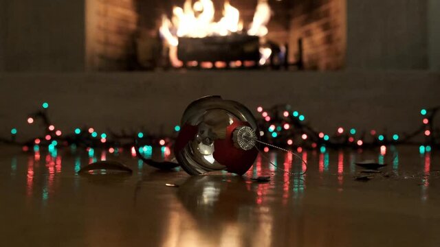 Christmas ball broken, colorful lights glowing, blur burning fireplace background