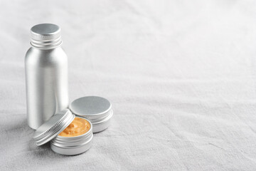 Set of metal containers of natural cosmetic products on linen fabric