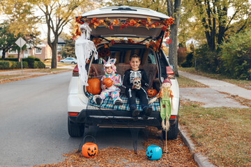 Trick o trunk. Siblings brother and sister celebrating Halloween in trunk of car. Children kids boy and baby girl celebrating October holiday outdoors. Social distance and safe alternative celebration