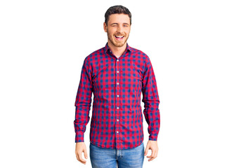 Handsome young man with bear wearing casual shirt winking looking at the camera with sexy expression, cheerful and happy face.