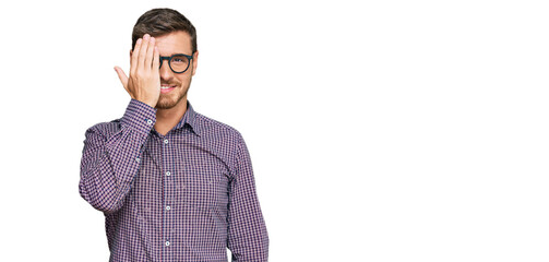 Naklejka premium Handsome caucasian man wearing casual clothes and glasses covering one eye with hand, confident smile on face and surprise emotion.