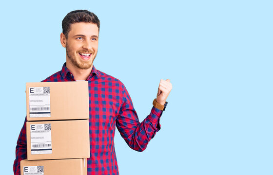 Handsome young man with bear holding delivery packages pointing thumb up to the side smiling happy with open mouth