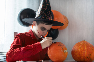 Halloween carnival or masquerade concept. Happy teen boy in costume drawing a pumpkin for the...