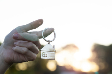 key chain in the form of a house in your hand of buying a home