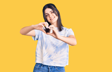 Young beautiful girl wearing casual t shirt smiling in love doing heart symbol shape with hands. romantic concept.