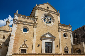 Fototapeta na wymiar Gravina in Puglia, Italy. The facade of the cathedral. The large central rose window and three portals. The large main door decorated with bas-reliefs and surmounted by a marble tympanum.