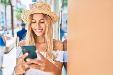 Young blonde tourist girl smiling happy using smartphone at the city.