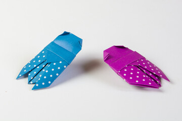 Two origami beatles made from purple and blue paper with white dots, isolated on blank background