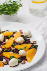 close-up plate of salad with mozzarella, orange, caramelized beetroot, sprouted sunflower and pistachios.