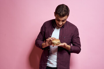 hungry man with hamburgers in hands fast food diet food emotions pink background