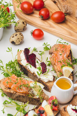 fresh red fish sandwich near by wooden board tomatoes and quail eggs