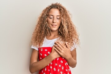 Beautiful caucasian teenager girl wearing red summer dress smiling with hands on chest with closed...