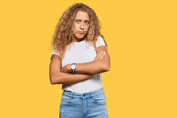 Beautiful caucasian teenager girl wearing casual white tshirt skeptic and nervous, disapproving expression on face with crossed arms. negative person.