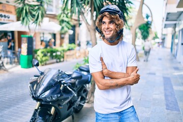 Young hispanic man smiling happy wearing moto helmet over motorcycle at the city