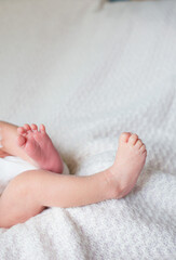 Newborn baby feet on a white blanket.