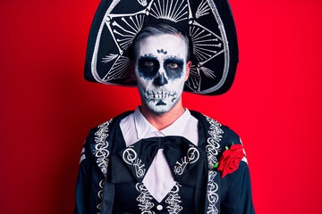 Young man wearing mexican day of the dead costume over red depressed and worry for distress, crying angry and afraid. sad expression.