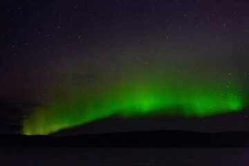 Obraz na płótnie Canvas View of the aurora borealis. Polar lights in the night starry sky over the lake.
