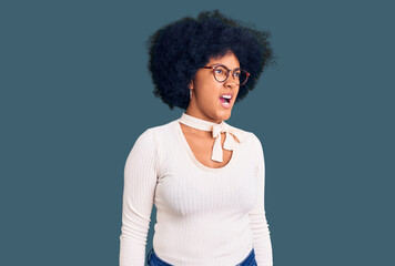 Fototapeta na wymiar Young african american girl wearing casual clothes and glasses angry and mad screaming frustrated and furious, shouting with anger. rage and aggressive concept.