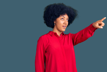 Fototapeta na wymiar Young african american girl wearing casual clothes pointing with finger surprised ahead, open mouth amazed expression, something on the front