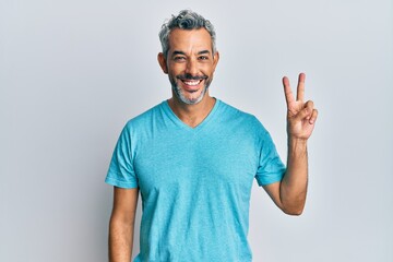 Fototapeta premium Middle age grey-haired man wearing casual clothes showing and pointing up with fingers number two while smiling confident and happy.