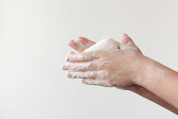 Two lathered hands hold soap between their palms on a white background. The concept of the need to wash hands to prevent diseases