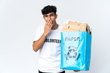 Young man holding a recycling bag full of paper happy and smiling covering mouth with hand