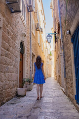 A girl in a blue dress walks along the narrow streets of the old city. Montenegro. Travel