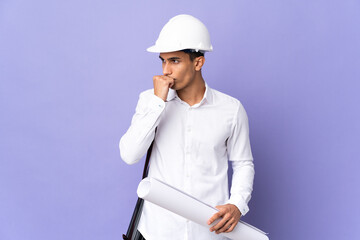 Young architect man isolated on background having doubts