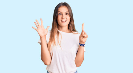 Fototapeta na wymiar Beautiful caucasian woman wearing casual white tshirt showing and pointing up with fingers number six while smiling confident and happy.