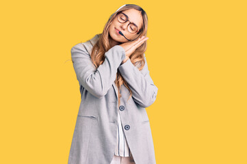 Young beautiful blonde woman wearing call center agent headset sleeping tired dreaming and posing with hands together while smiling with closed eyes.