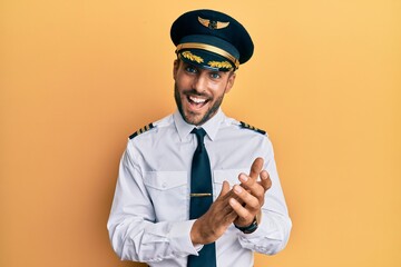Handsome hispanic man wearing airplane pilot uniform clapping and applauding happy and joyful, smiling proud hands together © Krakenimages.com