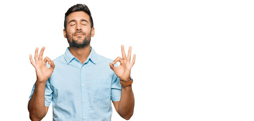 Handsome hispanic man wearing casual clothes relax and smiling with eyes closed doing meditation gesture with fingers. yoga concept.